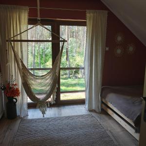a hammock hanging in a room with a window at Domek na wynajem Lgiń in Wschowa