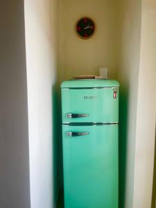 a green refrigerator in a corner with a clock on the wall at Accogliente stanzetta vicina al centro di Torino in Turin