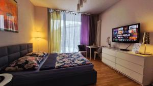 a bedroom with a bed and a dresser with a television at HomeComfort Apartament Gulia in Warsaw