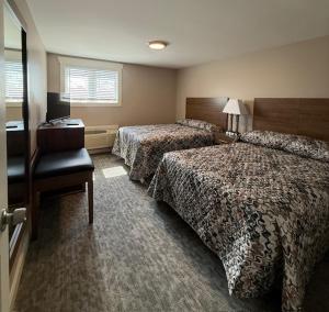 a hotel room with two beds and a desk at Mushroom Cap Motel in Mesick