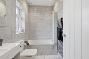 a bathroom with a tub and a toilet and a sink at Large, Bright 4 Bed Home with Garden in Kenton