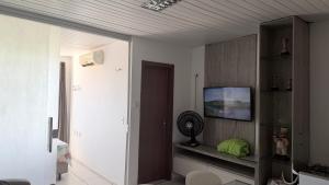 a living room with a tv on a wall at Flat Bela Amarração in Luis Correia