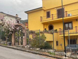 a yellow house with a fence next to a street at Villa Orchidea in Praia a Mare