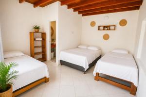 two beds in a room with white walls at Hotel Manglares in Capurganá