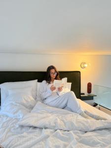 a woman sitting on a bed reading a book at Hvile in Kleszczyn