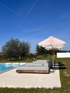 a group of lounge chairs under an umbrella next to a pool at Rusiborek Slow in Murzynowo Kościelne