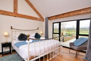 a bedroom with a bed and a chair and windows at Finest Retreats - Cae Rhug in Llanuwchllyn