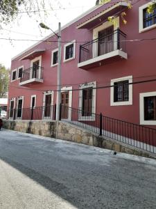 a pink building with balconies on a street at Antigua Mariana Hotel Boutique in Cedro