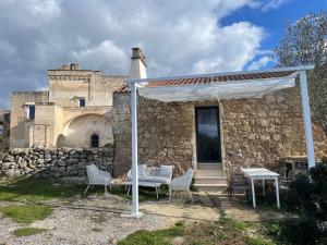 a stone house with a white canopy and chairs at Masseria Galeasi in Grottaglie