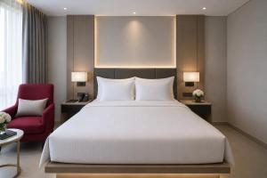a bedroom with a large bed and a red chair at Lagoon Beach Of The Arena Cam Ranh - Free room upgrade in Cam Ranh International Airport