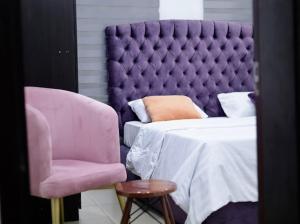 a bedroom with a purple bed and a chair at Uzzy Homes in Lagos