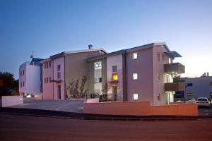 a large pink building on the side of a street at Apartmani Daška II in Njivice +19 photos