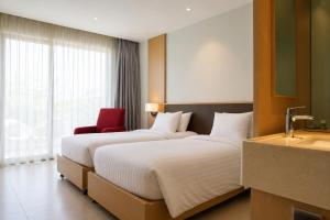 two beds in a hotel room with a red chair at Lagoon Beach Of The Arena Cam Ranh - Free room upgrade in Cam Ranh International Airport