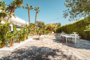 a patio with tables and chairs and palm trees at MareLuxe & Pool - Villa By The Sea in Polignano a Mare