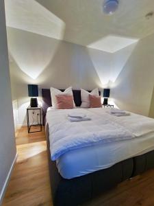 a bedroom with a large bed with white sheets and pink pillows at ARGENTA Living 42 in Künzell