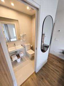 a bathroom with a toilet and a sink and a mirror at B&H Boreal in Burgos