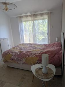 a bedroom with a bed and a window and a table at Maison moderne et lumineuse in Cavaillon