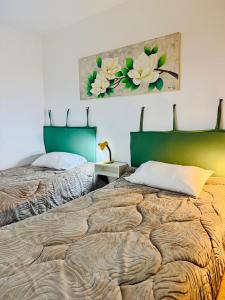 a bedroom with two beds and a painting on the wall at depto "A" 1 dormitorio centro in Trelew