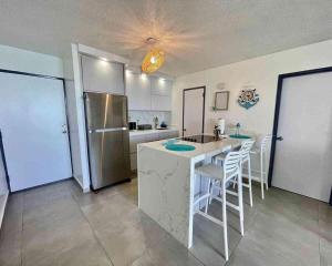 a kitchen with a sink and a counter with chairs at Private Island Oceanview Condo in Fajardo