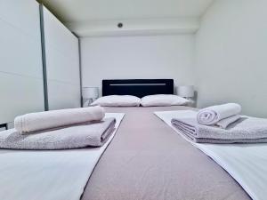 a white room with two beds with towels on them at Mini Lea in Jadranovo