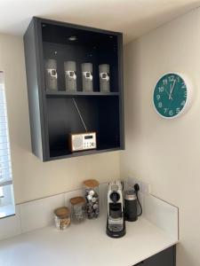 a kitchen with a counter with a clock and appliances at Milk Shed in Chard +9 photos