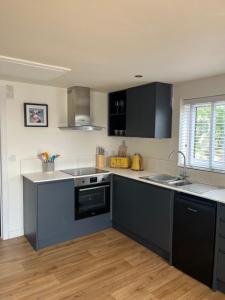 a kitchen with black and white cabinets and a sink at Milk Shed in Chard