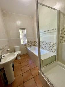 a bathroom with a tub and a sink and a toilet at Emmanuel Guest Villa in Thabazimbi +10 photos