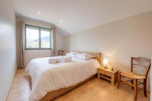 a bedroom with a large white bed and a chair at Villa Mareyland Saint-Jorioz, in Saint-Jorioz