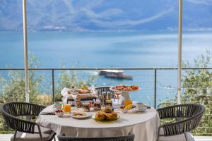 a table with food and a view of the ocean at Relax Hotel Villa Gardenia & Villa Oleandra in Limone sul Garda