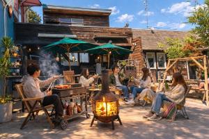 a group of people sitting in chairs around a fire at AJITO Chigasaki in Chigasaki