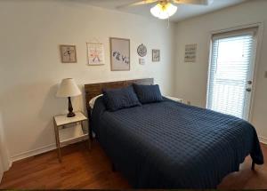 a bedroom with a bed with a blue comforter and a window at The Beach Peach in Port Aransas