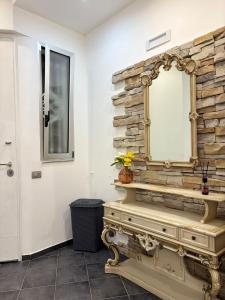 a bathroom with a mirror and a stone wall at B&B Fiore di Maggio in Mola di Bari