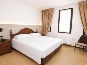 a bedroom with a large white bed and a window at Hotel Scala - Buongiorno! Hotels in Treviso