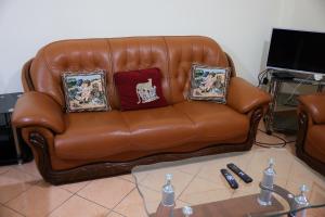 a brown leather couch with three pillows on it at Apartment Simon - Berat City Center in Berat