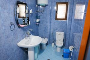 a blue tiled bathroom with a sink and a toilet at Apartment Simon - Berat City Center in Berat +14 photos