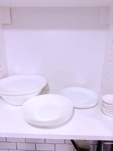 four white plates and bowls sitting on a kitchen counter at Large Private Suit With Free Parking in Mississauga +25 photos