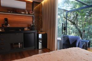 a living room with a kitchen and a large window at Cabanas Araucária in Campos do Jordão