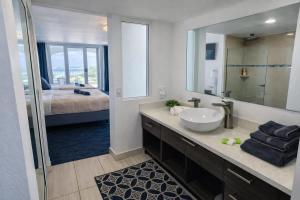 a bathroom with a sink and a mirror and a bed at Relaxing Ocean View Condo by the Beach in San Juan