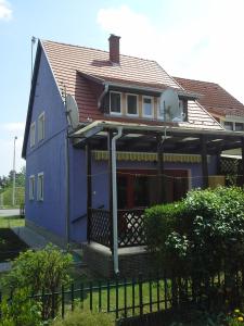 una casa azul con una valla delante de ella en Al Do Apartman, en Bük