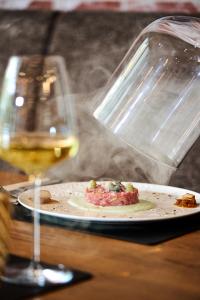 a glass of white wine next to a plate of food at Smarthotel Schmid - Restaurant & Bar inhouse - Nähe Schlossteich in Sitzenberg