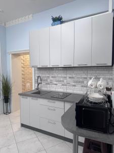 a kitchen with white cabinets and a sink and a table at Liders17 in Odesa +44 photos