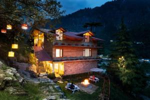 a house on a hill with a fire in front of it at The Pine Chalet Manali in Manāli