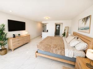 a bedroom with a large bed and a flat screen tv at Oceanview Beach Condo in Prime Location in San Juan