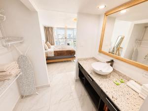a bathroom with a sink and a mirror and a bed at Oceanview Beach Condo in Prime Location in San Juan