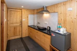 a kitchen with a sink and a refrigerator at The Pine Chalet Manali in Manāli