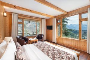 a bedroom with a bed and a large window at The Pine Chalet Manali in Manāli