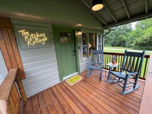 a porch with two chairs and a sign on it at Kitschy Kottage in Expansion