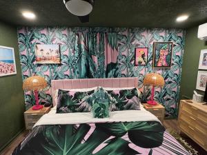 a bedroom with a bed with a tropical wallpaper at Kitschy Kottage in Expansion