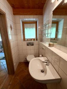 a bathroom with a sink and a toilet and a mirror at Ferienwohnung Am Bromberg in Schlehdorf +13 photos