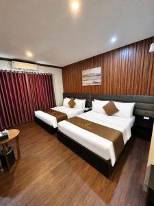 a hotel room with two beds and a table at Hotel Red River in Hà Ðông